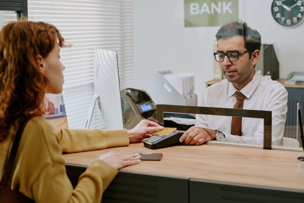 Customer,Engaging,With,Bank,Teller,During,Transaction,In,Modern,Bank Bond originator vs going direct to your bank — what’s the difference?